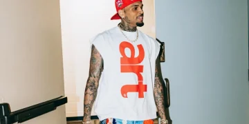 Chris Brown cammina con cappellino rosso e jeans patchwork