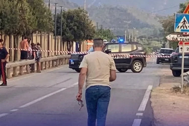 Uomo cammina su strada chiusa con auto Carabinieri e cordone di polizia