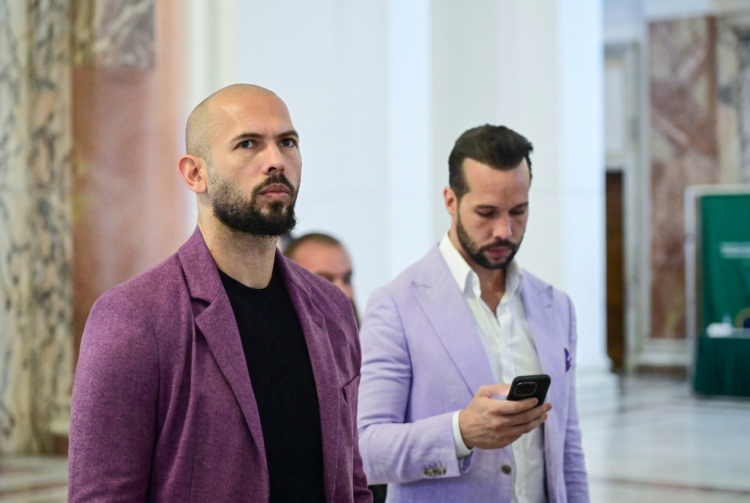 Andrew Tate con giacca viola guarda avanti con Tristan Tate al telefono. Fratelli Tate, custodia cautelare confermata a Miami: si oppongono all'estradizione nel Regno Unito