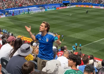 Tifoso italiano con maglia azzurra gesticola allo stadio durante una partita