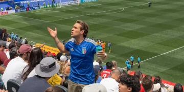 Tifoso italiano con maglia azzurra gesticola allo stadio durante una partita