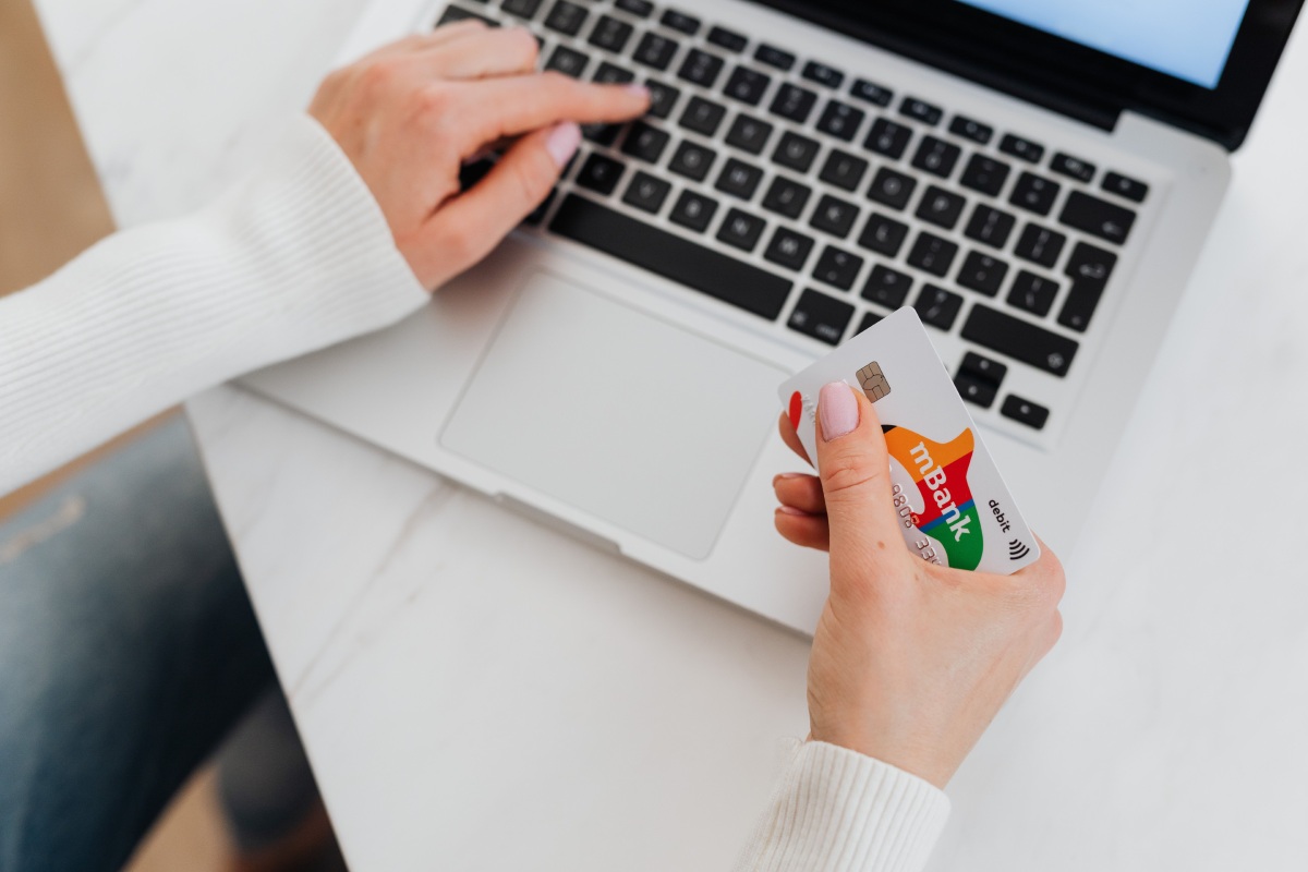 immagine di una donna con carta di credito in mano, pronta per pagare online