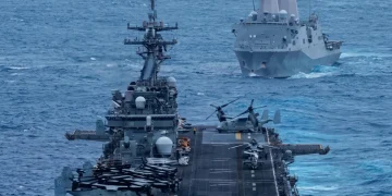 Due navi da guerra navigano nell'oceano, una con elicotteri a bordo.