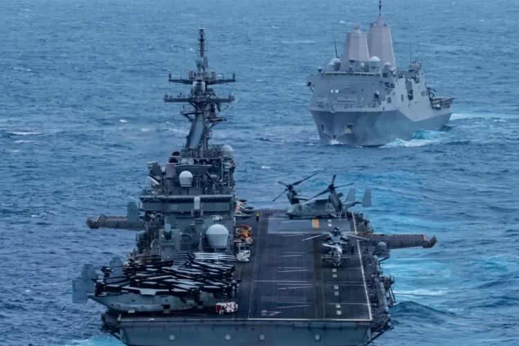 Due navi da guerra navigano nell'oceano, una con elicotteri a bordo.