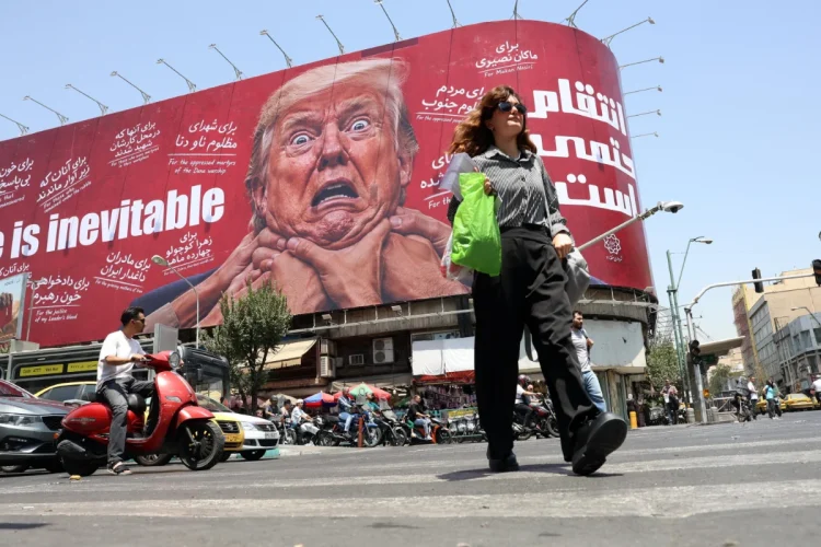 Donna iraniana cammina, tabellone anti-USA con Trump in strada a Tehran.
