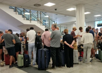 Folla di viaggiatori in attesa all'interno di un moderno aeroporto.