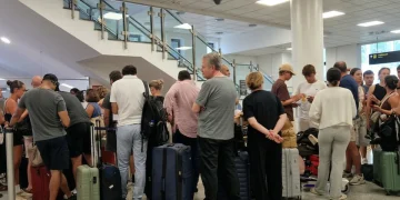 Folla di viaggiatori in attesa all'interno di un moderno aeroporto.