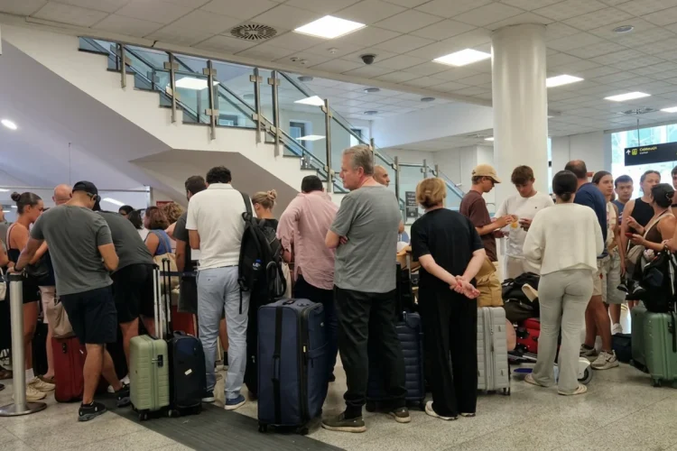 Folla di viaggiatori in attesa all'interno di un moderno aeroporto.