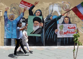an-iranian-couple-walks-next-to-a-anti-us-and-israel-mural-in-a-street-in-tehran-1200x800.webp