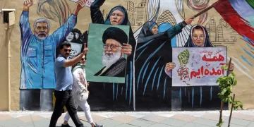 an-iranian-couple-walks-next-to-a-anti-us-and-israel-mural-in-a-street-in-tehran-1200x800.webp