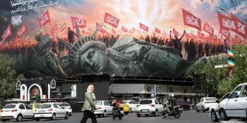 An Iranian elderly woman walks past an anti-US billboard at Enghelab Square in central Tehran, Iran, 03 August 2026
