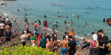 Giovani e migranti in acqua e sulla spiaggia di Ceuta.