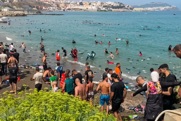 Giovani e migranti in acqua e sulla spiaggia di Ceuta.