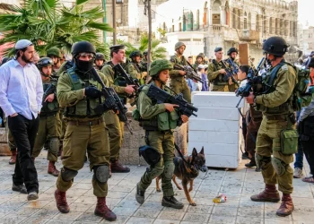 Soldati israeliani pattugliano strada con un colono ebreo ortodosso.