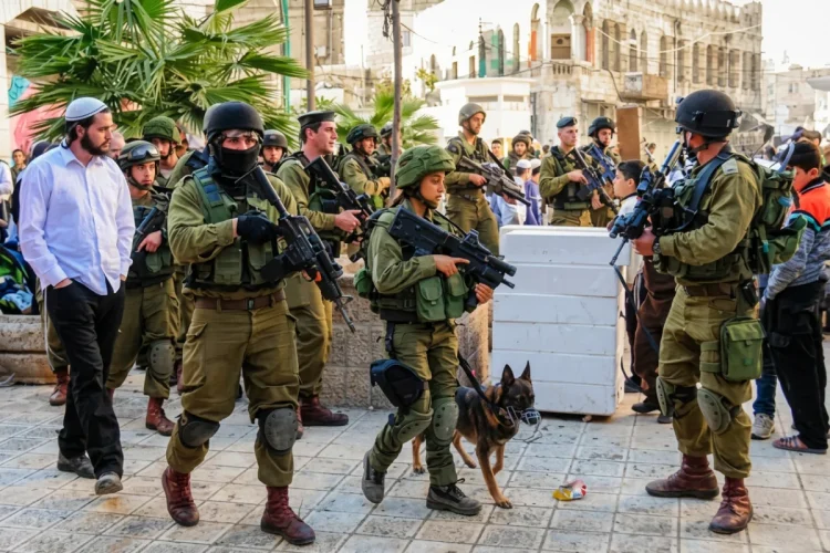 Soldati israeliani pattugliano strada con un colono ebreo ortodosso.