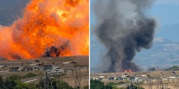 Esplosione con palla di fuoco e colonna di fumo nero su edifici