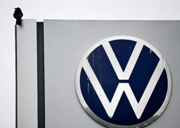 Corvo posato accanto al logo Volkswagen su un insegna.