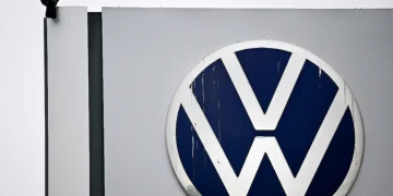 Corvo posato accanto al logo Volkswagen su un insegna.