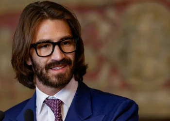 Leonardo Del Vecchio Jr. sorride indossando occhiali neri e giacca blu.