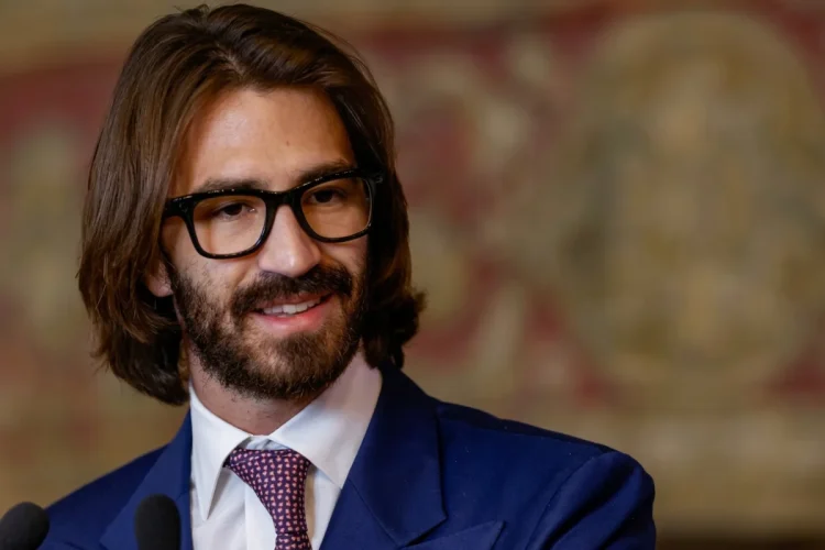 Leonardo Del Vecchio Jr. sorride indossando occhiali neri e giacca blu.