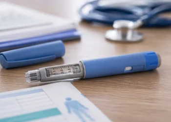 Penna per insulina blu e grigia con ago su tavolo medico