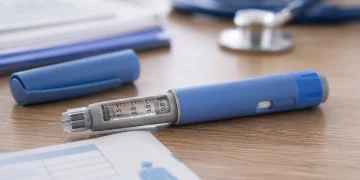 Penna per insulina blu e grigia con ago su tavolo medico