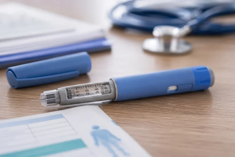 Penna per insulina blu e grigia con ago su tavolo medico