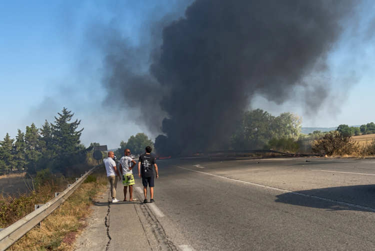 Uomini osservano denso fumo nero da incidente a bordo strada. Atterraggio d'emergenza a Salon-de-Provence: aereo dell'Aeronautica militare prende fuoco