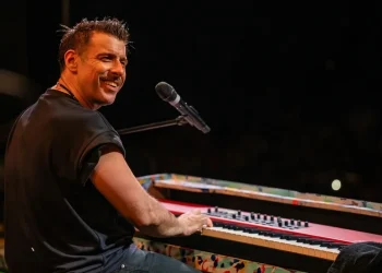 Francesco Gabbani sorride e suona la tastiera durante un concerto.