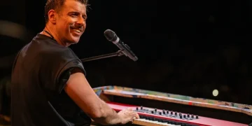 Francesco Gabbani sorride e suona la tastiera durante un concerto.