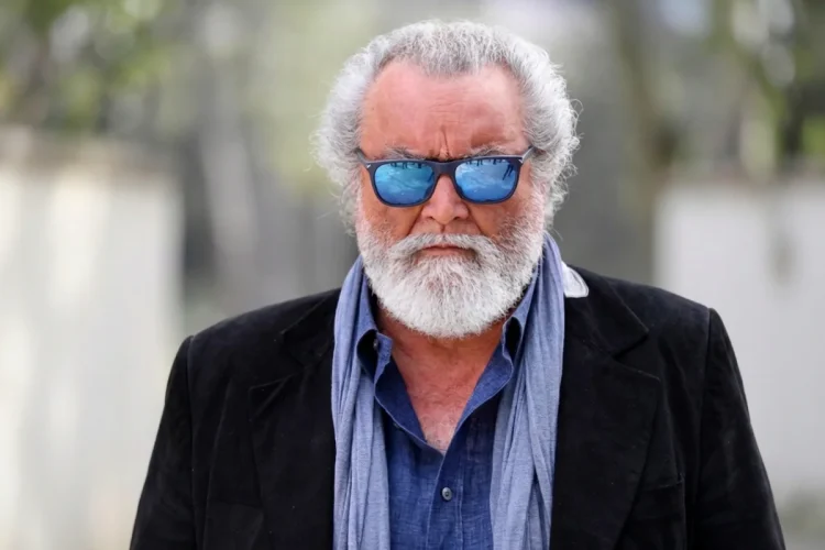 Diego Abatantuono con occhiali da sole blu e barba grigia folta.