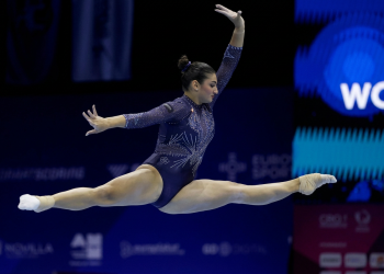Ginnasta esegue elegante spaccata aerea in body blu brillante. Europei di ginnastica artistica: Manila Esposito medaglia d'oro