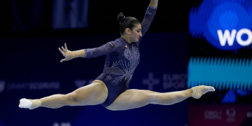 Ginnasta esegue elegante spaccata aerea in body blu brillante. Europei di ginnastica artistica: Manila Esposito medaglia d'oro