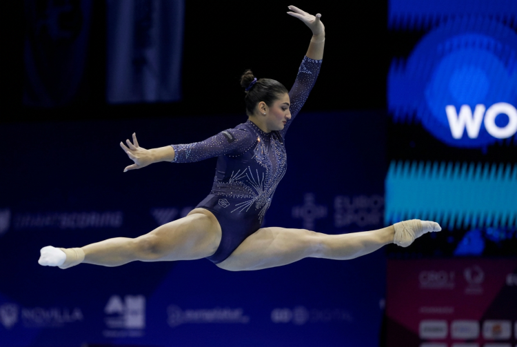 Ginnasta esegue elegante spaccata aerea in body blu brillante. Europei di ginnastica artistica: Manila Esposito medaglia d'oro