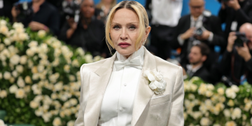 Madonna in completo chiaro con papillon e fiore bianco sul tappeto rosso. Madonna conquista il maggior numero di nomination ai MTV Video Music Awards superando Taylor Swift