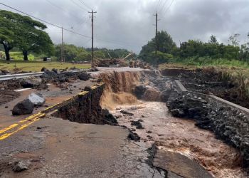 Strada distrutta dall'alluvione con acqua fangosa che scorre, detriti e escavatore. Uragano Lala alle Hawaii tra piogge torrenziali e blackout: oltre 200mila famiglie senza corrente