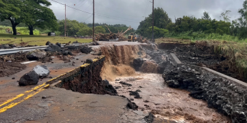 Strada distrutta dall'alluvione con acqua fangosa che scorre, detriti e escavatore. Uragano Lala alle Hawaii tra piogge torrenziali e blackout: oltre 200mila famiglie senza corrente