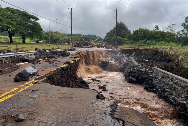 Strada distrutta dall'alluvione con acqua fangosa che scorre, detriti e escavatore. Uragano Lala alle Hawaii tra piogge torrenziali e blackout: oltre 200mila famiglie senza corrente