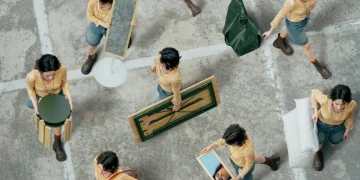 Ragazza sposta mobili IKEA e oggetti domestici su pavimento in cemento.