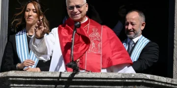 Cardinale sorridente saluta da balcone con collaboratori a San Marino