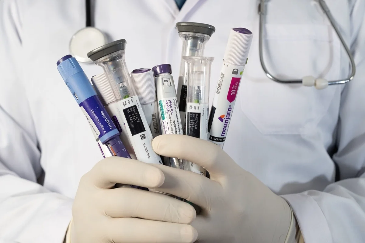 Medico con guanti tiene iniettori di Mounjaro e Liraglutide
