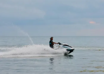 Uomo con giubbotto salvagente guida una moto d'acqua sul mare di Koh Samui, Thailandia