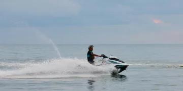 Uomo con giubbotto salvagente guida una moto d'acqua sul mare di Koh Samui, Thailandia