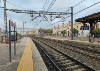 Binari del treno vuoti in stazione con banchina gialla.