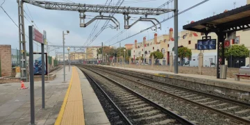 Binari del treno vuoti in stazione con banchina gialla.