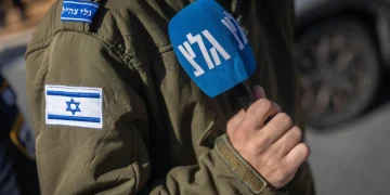 Soldato israeliano con bandiera e microfono di Galei Tzahal (Army Radio)