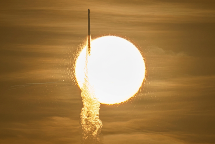 Razzo si lancia con scia luminosa davanti a un corpo celeste brillante. Il telescopio spaziale Roman lanciato da Cape Canaveral: parte la missione su materia ed energia oscura