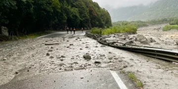 Vigili del fuoco camminano su strada invasa da fango e sassi