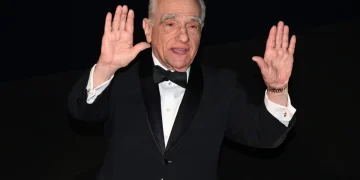 Martin Scorsese saluta con le mani alzate in smoking nero