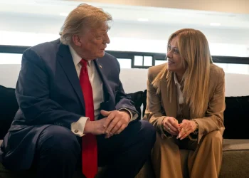 Donald Trump e Giorgia Meloni siedono sorridendo, conversano animatamente sul divano.
